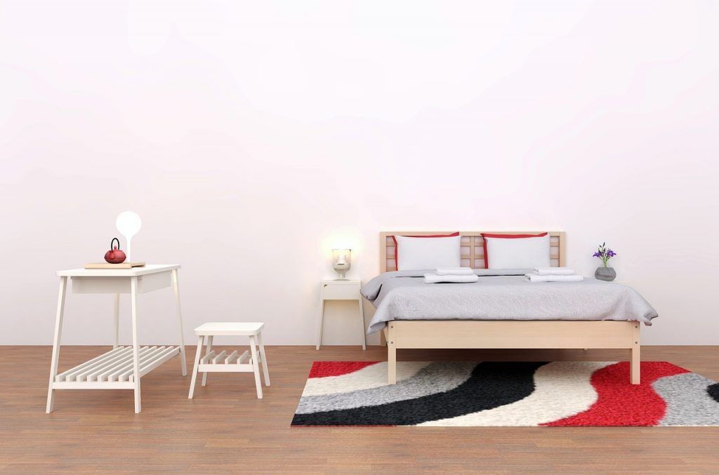 chambre moderne avec lit beige, mobilier blanc et tapis coloré sur parquet