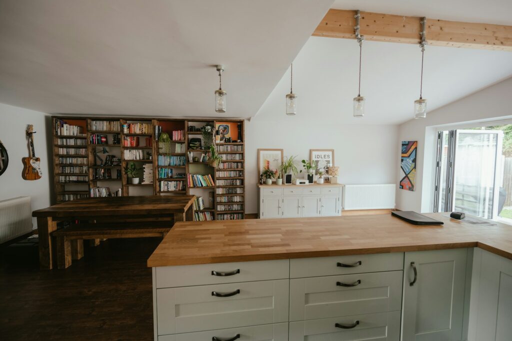 cuisine ouverte moderne avec îlot central en bois, rangements verts et bibliothèque intégrée