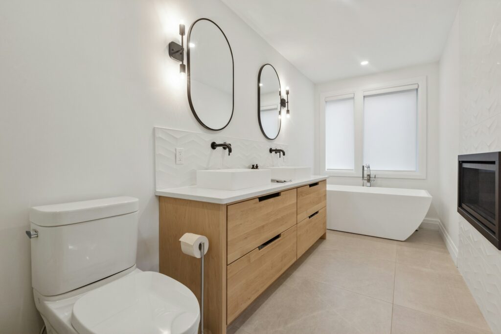 salle de bain moderne design avec vanité bois, doubles miroirs et baignoire blanche
