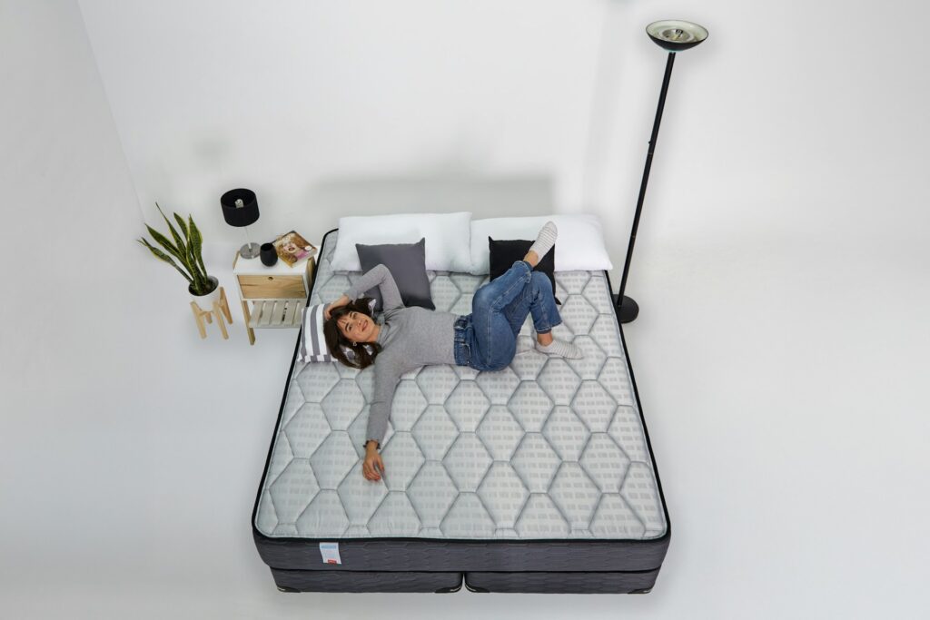 femme allongée sur un matelas gris clair vue de dessus dans une chambre minimaliste