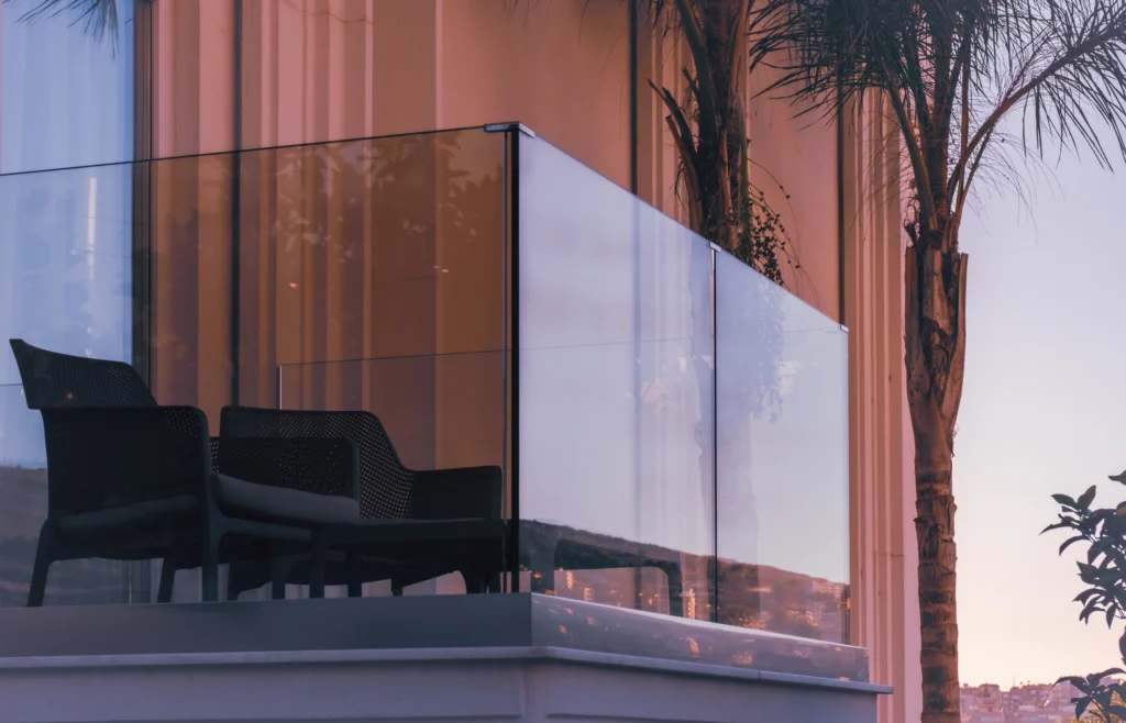 garde-corps en verre transparent sur balcon avec chaises noires et vue sur paysage