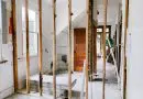Interior view of a home under renovation with exposed wooden beams and door.
