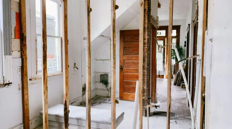 Interior view of a home under renovation with exposed wooden beams and door.